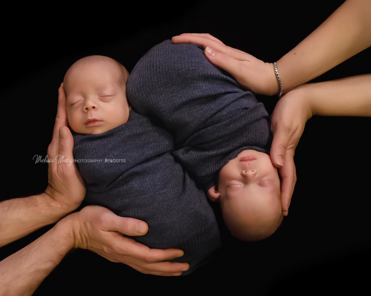twin newborn baby boys snuggled in their parents arms oakland county mi
