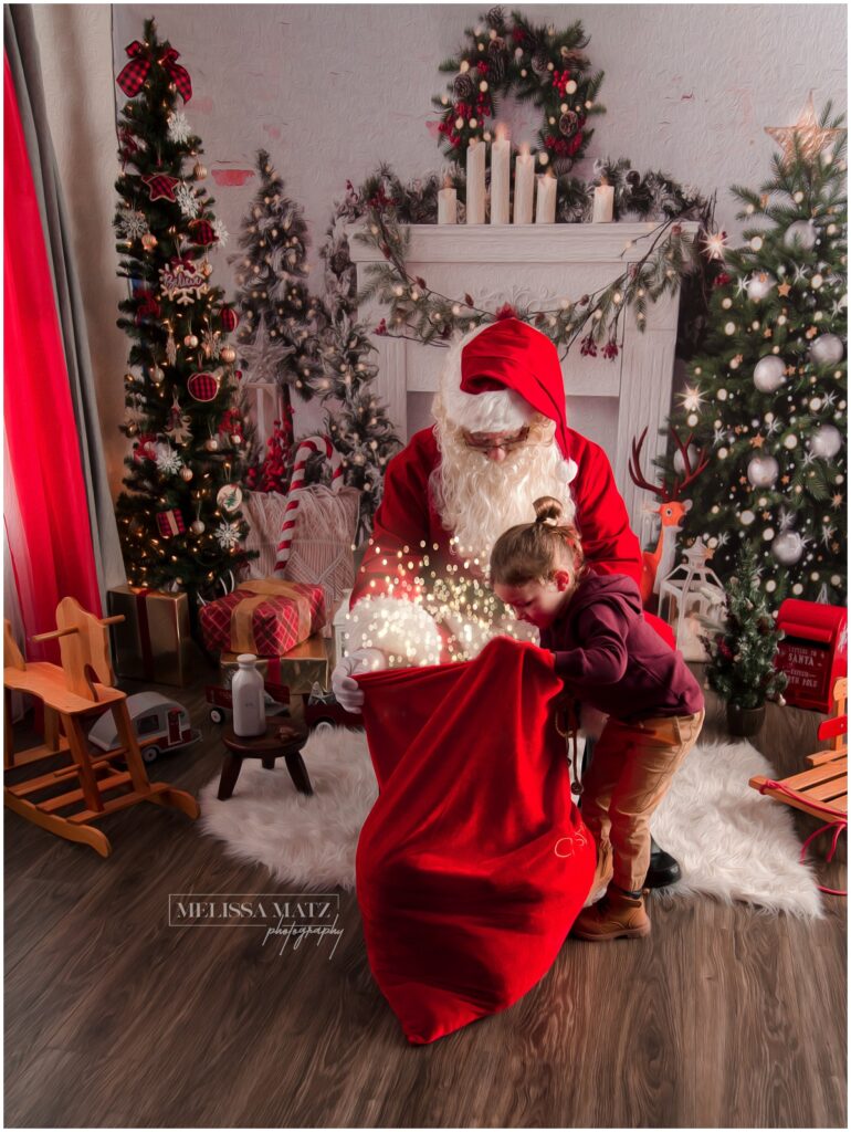 magical photo of Santa and a little one looking through his bag at a photo session in shelby township mi