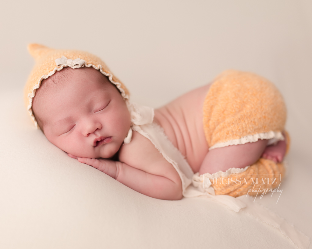 newborn baby dressed in yellow outfit