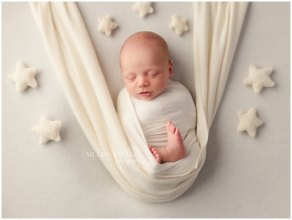 swaddle wrapped newborn sleeping surrounded by tiny stars