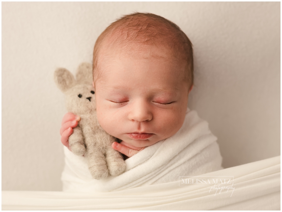 close up image of a sleeping newborn baby holding a tiny bunny