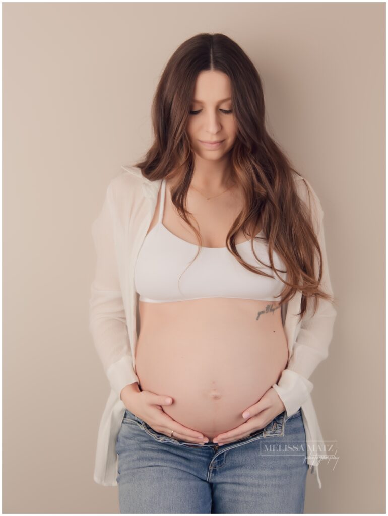 expecting mom to be in jeans and tank top at her maternity studio session