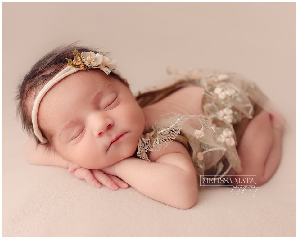 Close-up of newborn with cream floral headband and soft neutral tones, styled by Shelby Township MI newborn photographer.