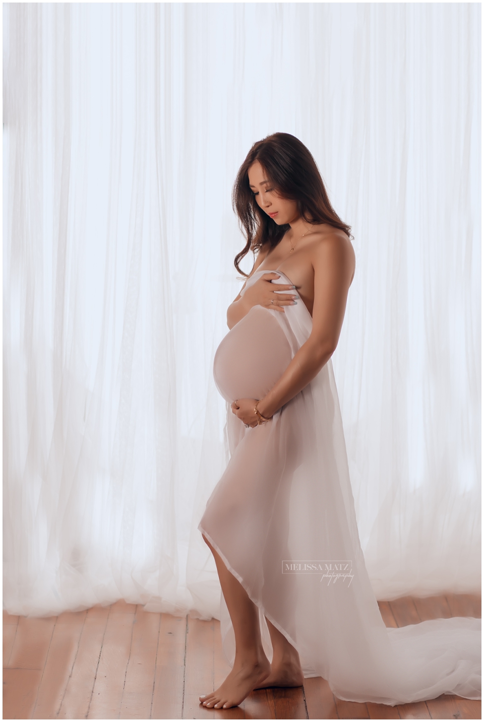 Confident mom-to-be draped in sheer fabric during intimate maternity photo session Metro Detroit boudoir photographer