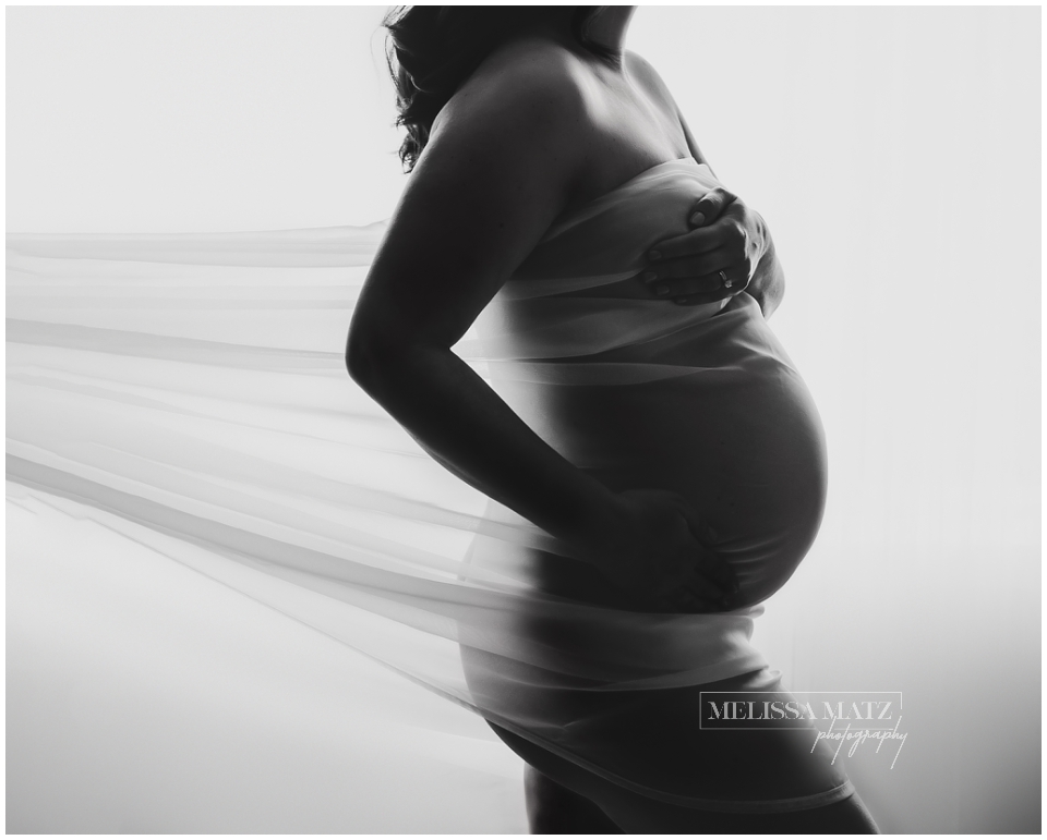 Moody maternity boudoir portrait using shadow and light to highlight curves