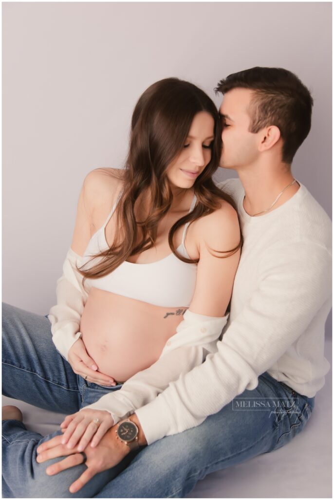 parents to be sitting together during their maternity session in melissa matz photography studio