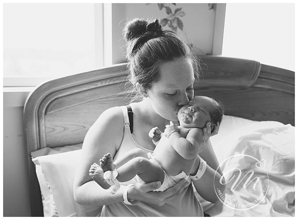 new mom kissing her brand new baby in the hospital room during their fresh 48 session in rochester hills mi