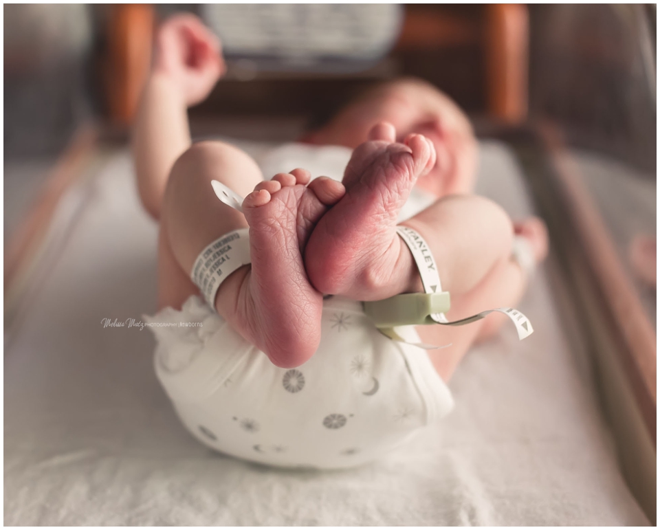 newborn baby 48 hours old in hospital bassinet with his tiny feet curled up