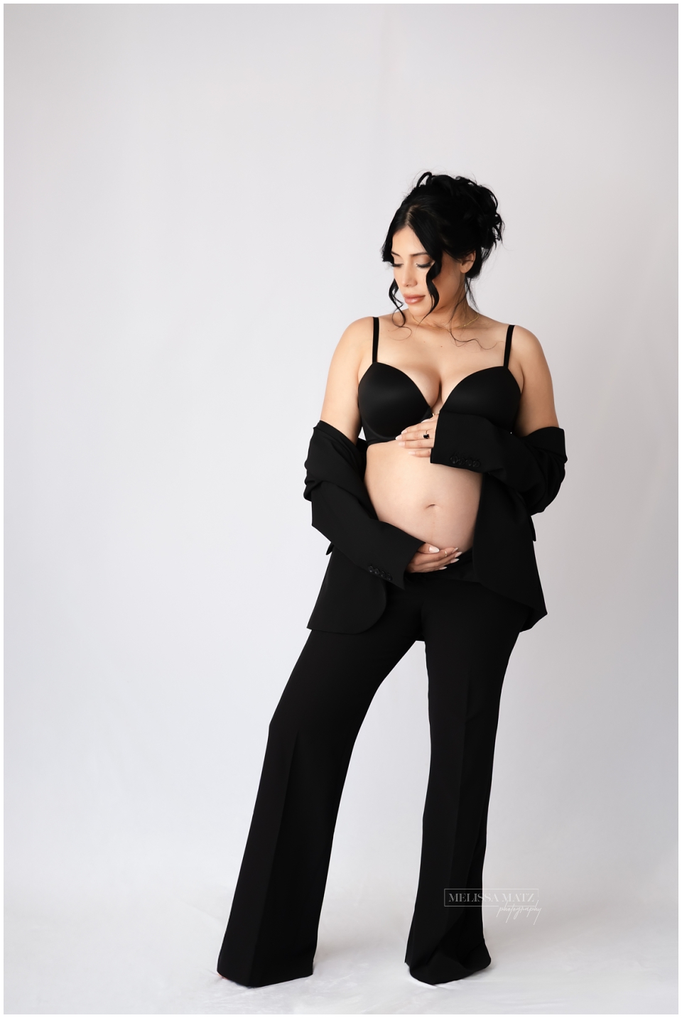 elegant maternity photo mom to be wearing black blazer with bra during their session in metro detroit studio