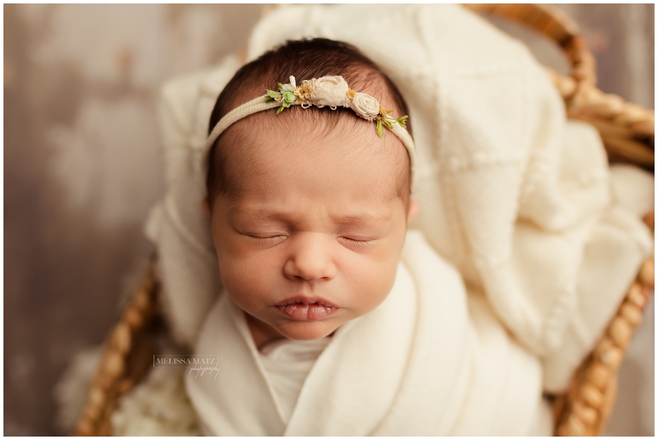 closeup newborn portrait with soft neutral colors and floral headband