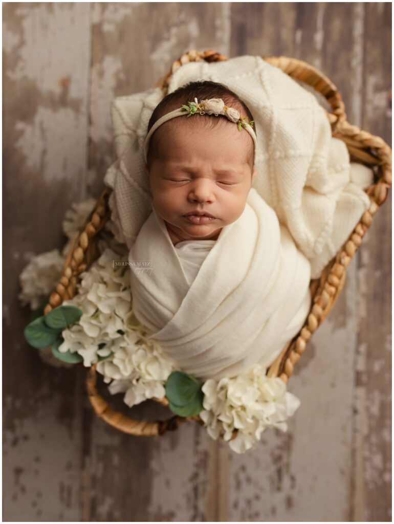 newborn photo neutral tones soft fabric floral accents