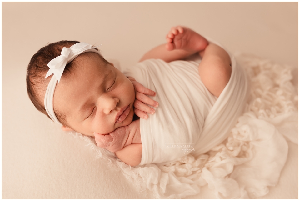 swaddle wrapped newborn posed asleep on lace during her newborn session with melissa matz photography