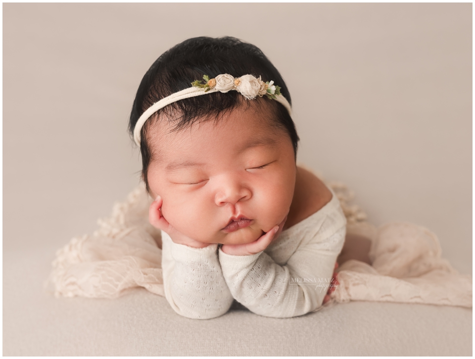 newborn froggy pose floral headband on cream fabric