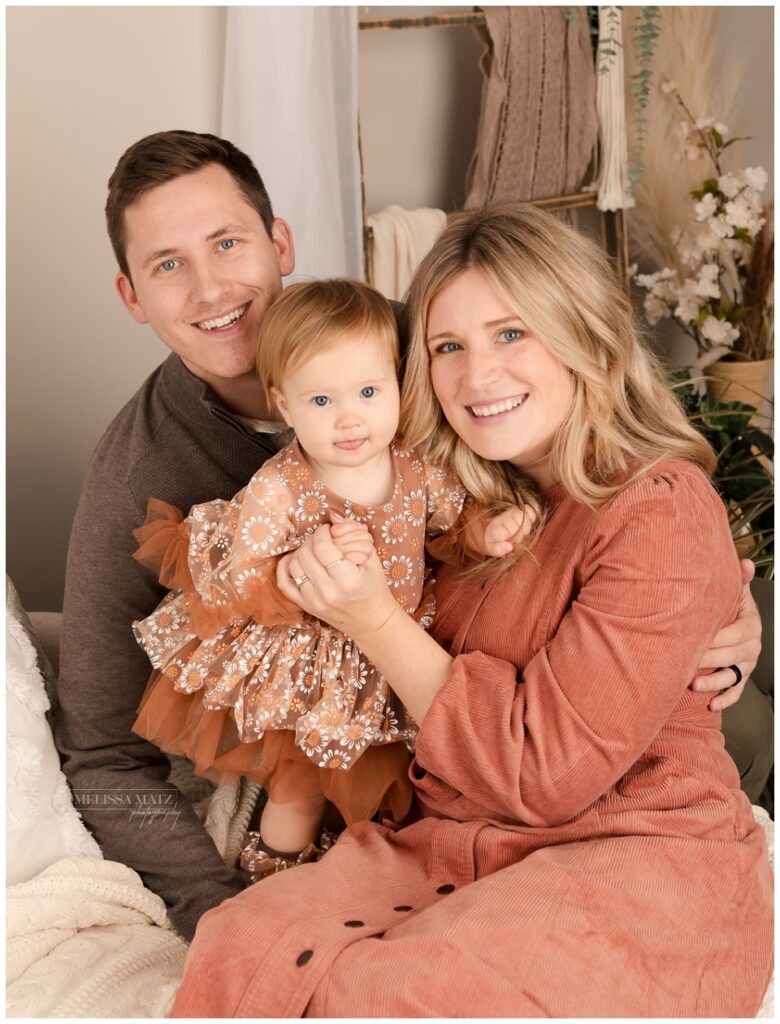 family photo dressed in warm colors at their one year milestone studio session