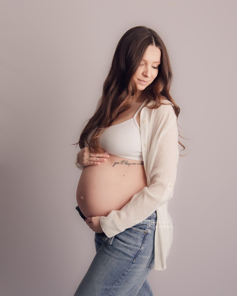 mom to be dressed in jeans and white tank top during her mini maternity session