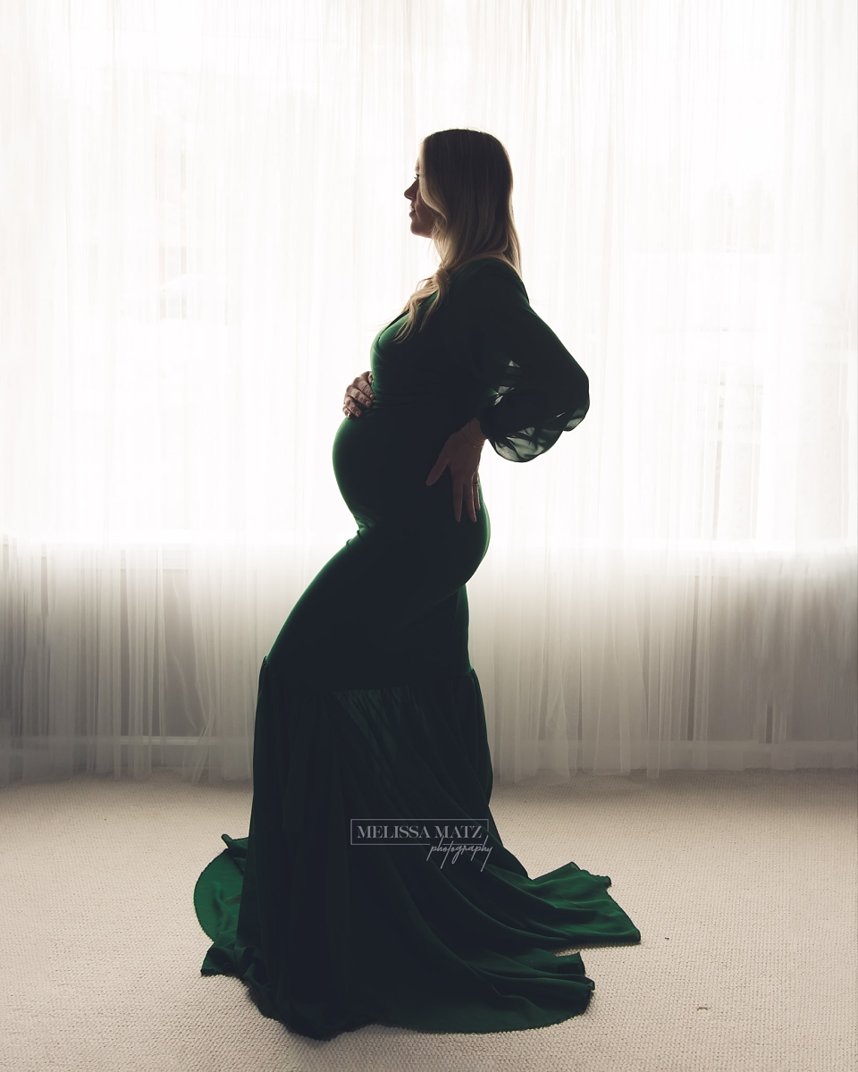 dramatic backlit image with dark tones in a green flowing dress