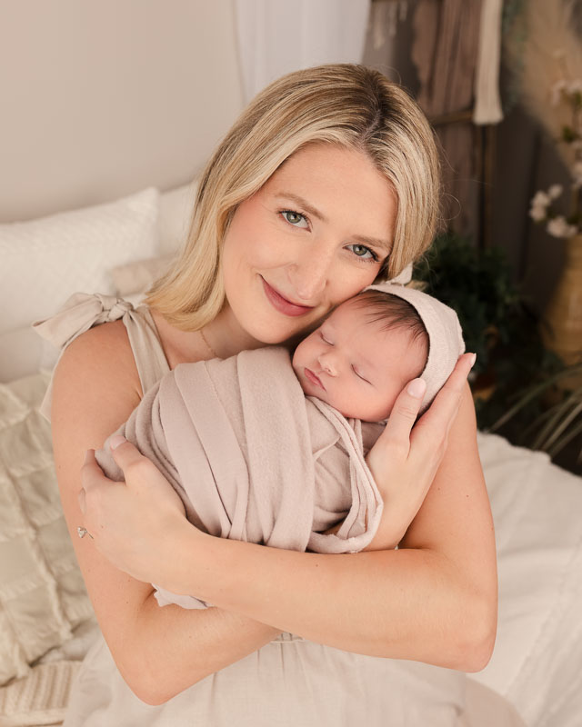 Metro Detroit newborn photographer captures mother tenderly holding her newborn baby during an in-studio session in Shelby Township MI