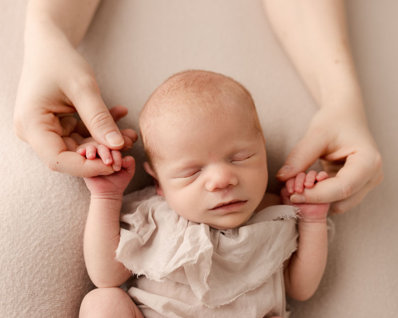 Close up of newborn baby hands held by mother, photographed by a Metro Detroit newborn and family photographer in Shelby Township MI