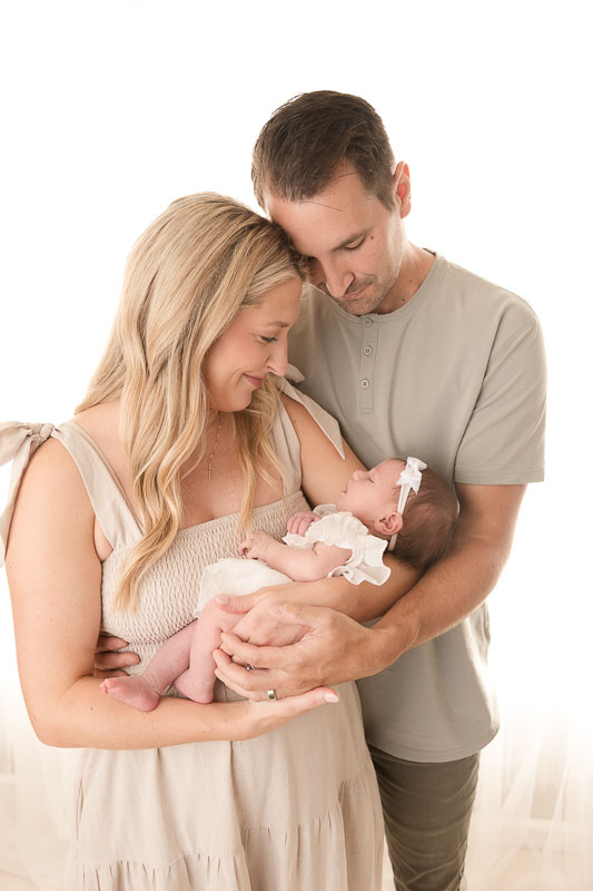 Mother in a flowy dress holding her newborn baby during a studio photography session