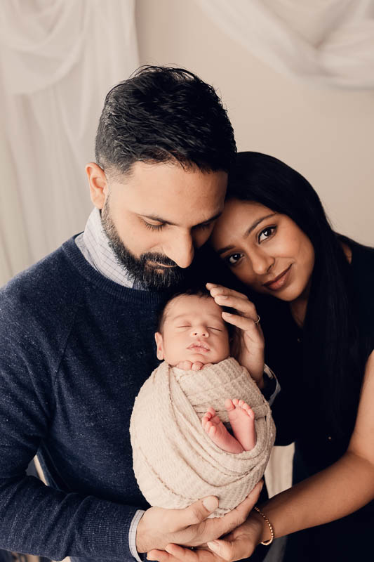 New family wearing cream and navy coordinated outfits during a studio newborn session in Shelby Township Michigan