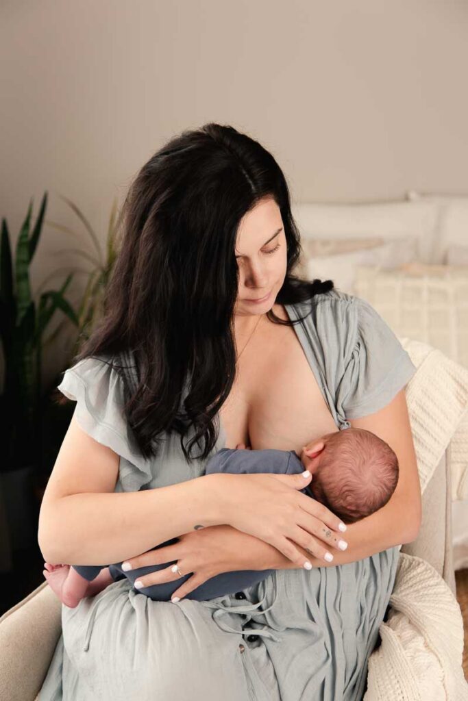 nursing mother cradling her newborn during their nursing session in shelby township photo studio