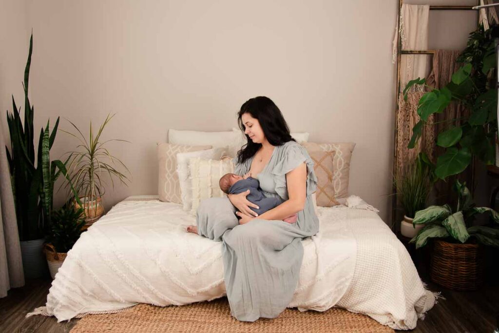 wide angle photo of mom nursing her newborn baby nestled in her arms during their photo session