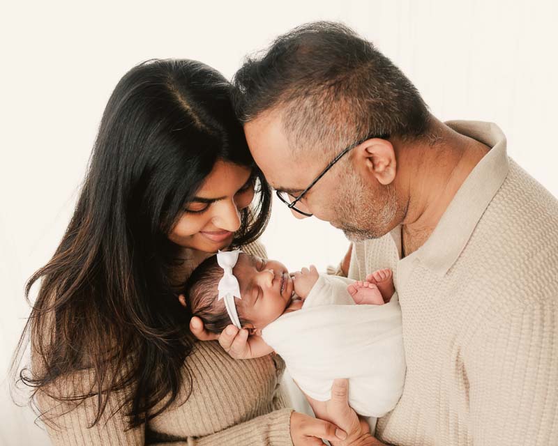 Parents cuddling their 2 week old newborn baby during in-studio newborn session