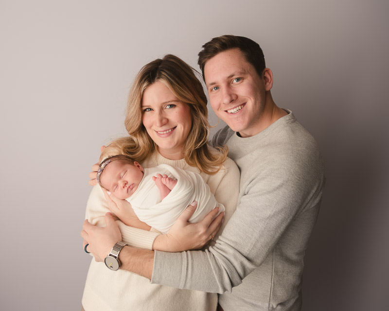 Family in coordinated neutral outfits during a newborn session at Melissa Matz Photography studio in Shelby Township