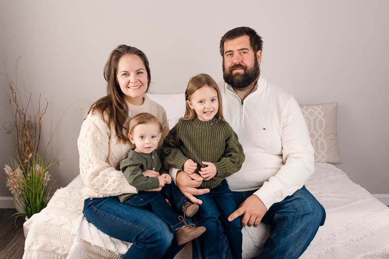 Family with one year old and older sibling in coordinated neutral outfits during a studio milestone session
