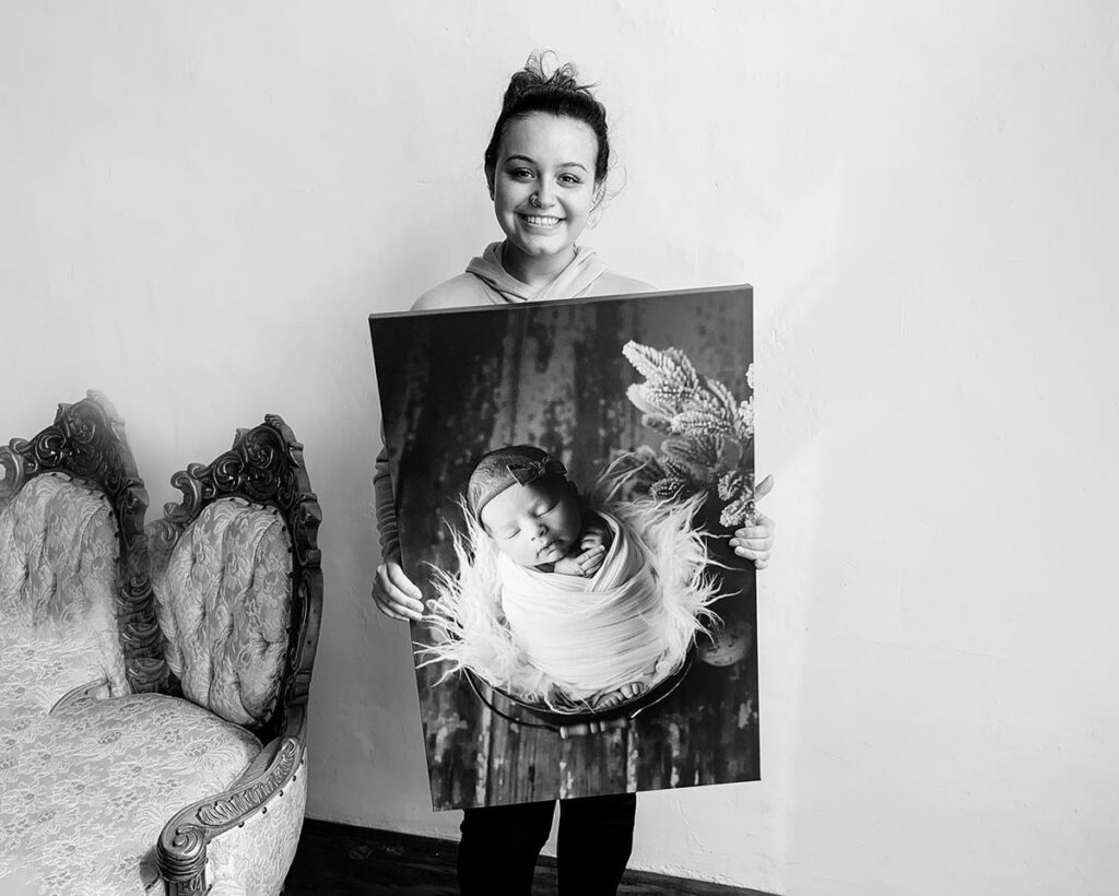 Client holding a large canvas print of her newborn session at Melissa Matz Photography in Shelby Township Michigan