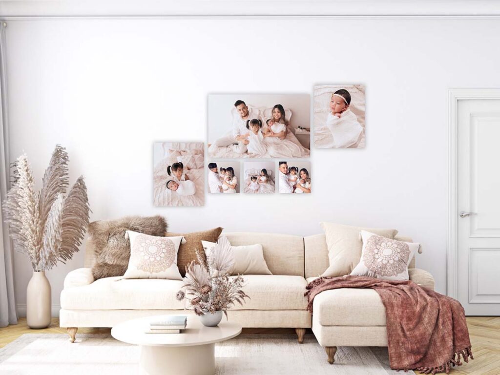 Newborn and family photos displayed as canvas wall art grouping above a sofa in a light neutral living room