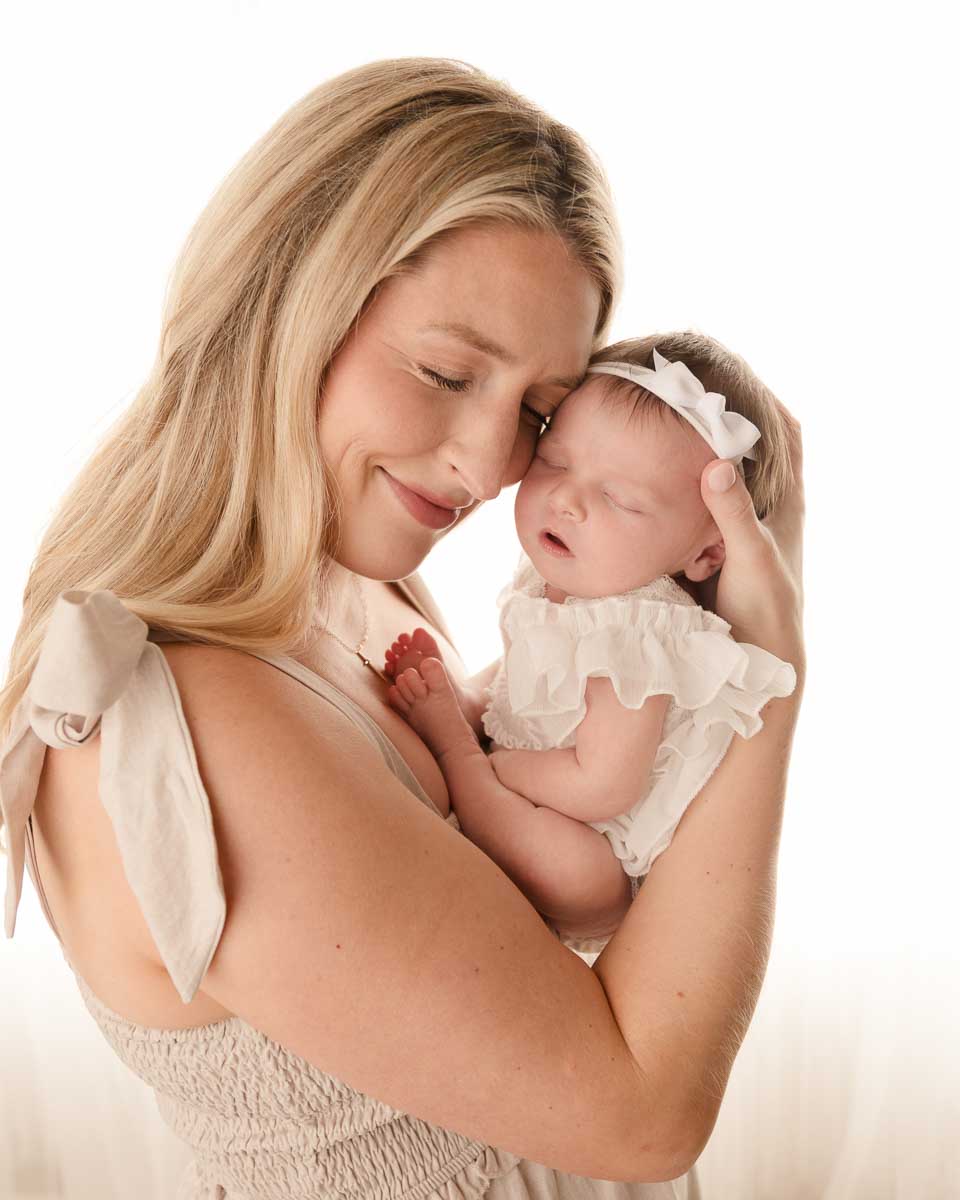 Mother holding her newborn baby girl cheek to cheek with eyes closed during a studio newborn session at Melissa Matz Photography in Shelby Township Michigan