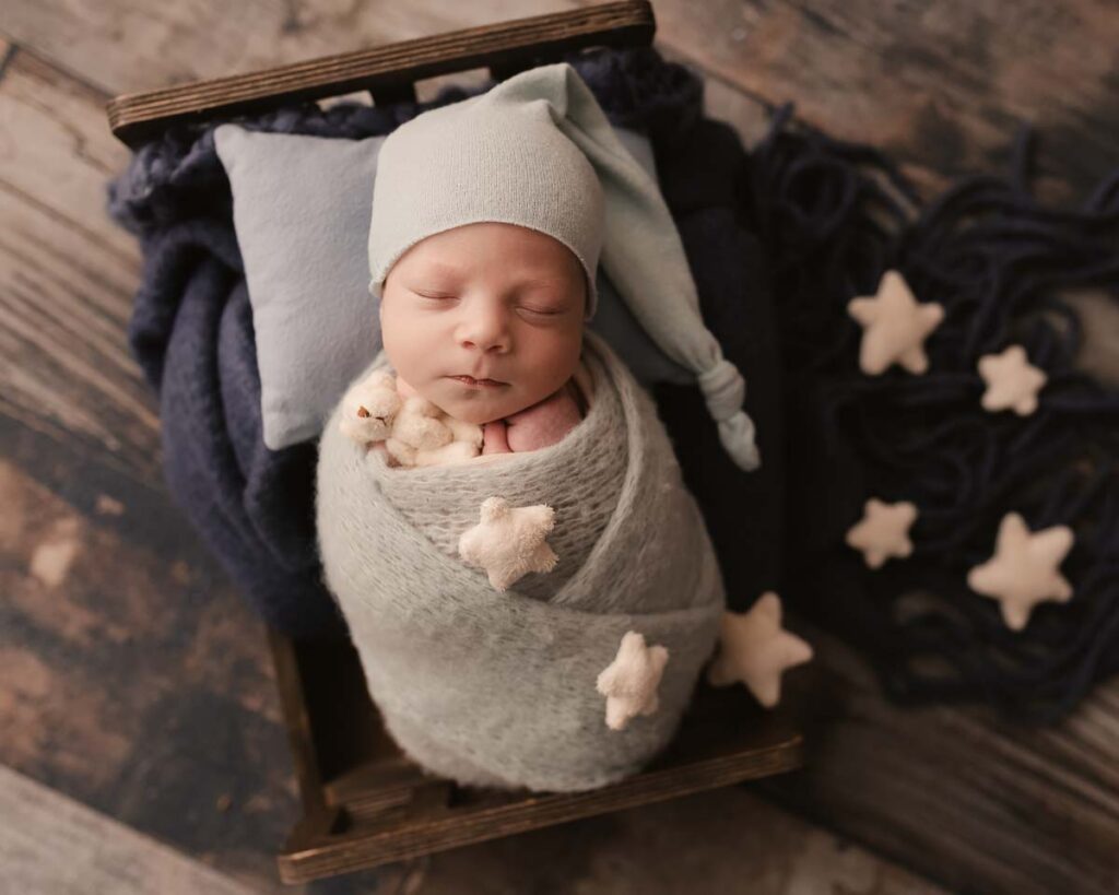 swaddled newborn baby in star props during posed newborn photo session Macomb County Michigan
