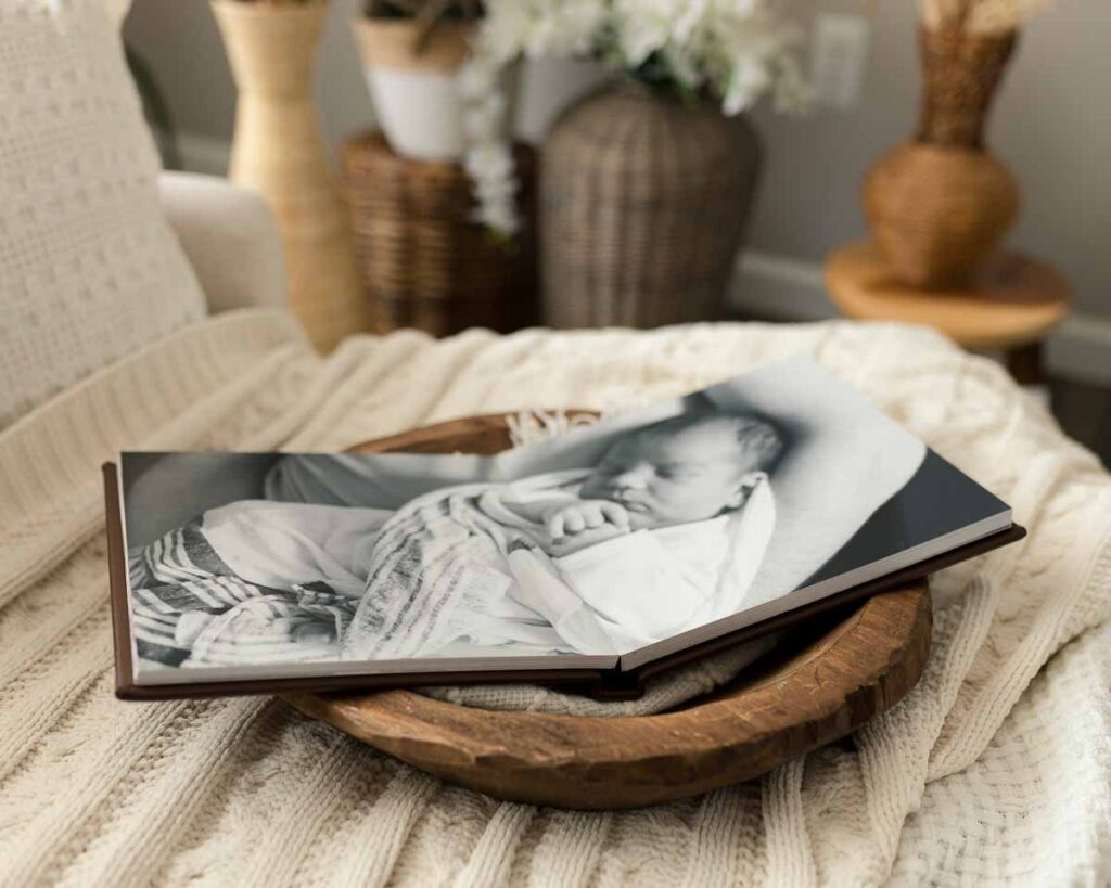 Open newborn photo album showing printed portraits from a Metro Detroit baby's first days